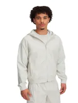 Campera deportiva con capucha color gris claro, con cierre frontal y bolsillos laterales. Tiene puños y cintura elastizados.