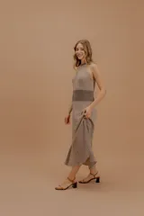 Vestido midi tejido de punto con diseño sin mangas y cuello halter. Presenta una silueta fluida con un panel de contraste en tono más claro a la altura de la cintura. Confeccionado con hilados italianos y sutiles toques de lurex.