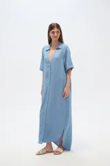 Vestido largo tipo camisero de lyocell, con cuello camisero, cierre frontal de botones, mangas cortas con dobladillo y bolsillos laterales. Presenta un corte holgado y tajos laterales en el ruedo.
