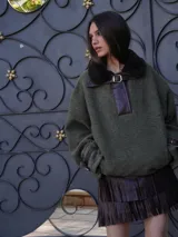 Buzo verde con cuello de piel sintética marrón, cierre parcial con hebilla y puños ajustables con hebilla.