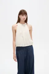 Musculosa sin mangas color natural, confeccionada en viscosa, con cuello redondo base con frunces y elástico en la parte inferior.