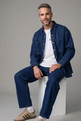 Sobrecamisa de jean color azul oscuro, de corte oversize, con mangas largas, bolsillos frontales con solapa y cierre con broches a presión.