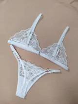 Conjunto de lencería de dos piezas confeccionado en encaje blanco con diseño floral. Incluye un soutien tipo triángulo con tirantes regulables y una bombacha tipo colaless con tiras laterales ajustables.