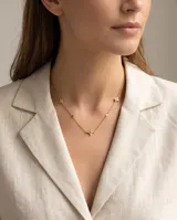 Collar de cadena fina con baño de oro, adornado con pequeños dijes en forma de estrella de cuatro puntas con incrustaciones de circonias.