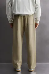 Pantalón jogger de corte relajado confeccionado en tejido compacto de algodón. Presenta cintura elástica con cordón interior, bolsillos frontales en la cadera y un bolsillo trasero de plastrón.