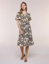 Vestido midi de rayón en color beige con estampado floral en negro, escote en V, pechera con punto smock, mangas cortas acampanadas con detalle de galón y falda evasé con volado en el ruedo. Incluye lazo textil ajustable en la cintura.