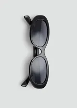 Lentes de sol con armazón de policarbonato negro y diseño de montura ovalada angosta estilo retro.
