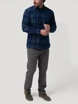 Camisa de manga larga para hombre, con estampado de cuadros tartán en tonos azul, gris y marrón. Presenta cuello clásico, cierre frontal de botones y dos bolsillos con solapa en el pecho.