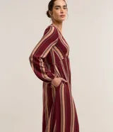 Vestido largo evasé de Marfinno, confeccionado en mezcla de viscosa y lino, con diseño de rayas verticales en tonos bordó y beige. Presenta escote en V, busto ajustado y mangas largas abullonadas con puños elastizados.