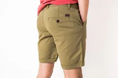 Bermuda de gabardina color verde oliva, con cierre de botón y bragueta, bolsillos laterales y dobladillo en las piernas.