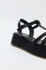 Sandalia de plataforma color marrón con tiras trenzadas y pulsera con hebilla.