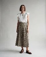 Blusa blanca de lino con mangas cortas con volados y cuello redondo, de corte recto y diseño minimalista.