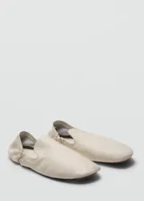 Zapatos tipo ballerinas planas de piel ovina en color blanco, con punta redonda, diseño sin cordones y detalle de fruncido elástico en el talón.