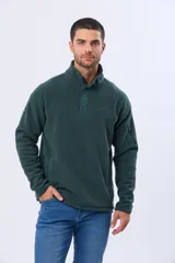 Buzo de polar térmico en color verde oscuro, con cuello alto y cierre frontal parcial con broches. Presenta bolsillos laterales con cierre y un bolsillo adicional con cierre en la manga izquierda.