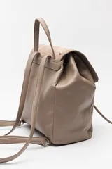 Mochila negra de símil cuero texturizado con tapa en acabado gamuzado, decorada con apliques de tachas metálicas. Tiene asa superior y correas regulables.