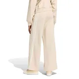 Pantalón deportivo Adidas de mujer, modelo Kit 3 Stripes, en color beige claro con las clásicas tres tiras blancas a los lados y el logo de la marca bordado en la pierna izquierda. Cuenta con cintura elástica y diseño de pierna ancha.