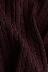 Buzo de tejido punto color bordó, con escote redondo pronunciado y manga larga. Presenta un diseño de punto trenzado a lo largo de todo el cuerpo y remates acanalados en cuello, puños y bajo.