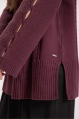 Sweater de punto color bordó con cuello alto y diseño de trenzas en el frente y las mangas. Presenta un corte holgado y largo, con puños y ruedo acanalados.