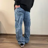 Jean cargo de corte baggy en color azul lavado, con múltiples bolsillos laterales tipo cargo y cierre frontal.