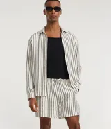 Bermuda de playa con diseño de rayas verticales, confeccionada en tejido texturizado de secado rápido. Cuenta con cintura elástica ajustable mediante cordón y bolsillos laterales.