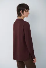 Cardigan de punto color beige, con cuello camisero, cierre frontal de botones y bolsillo aplicado en el pecho. Presenta mangas largas con puños acanalados y un corte recto y holgado.