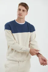 Sweater deportivo de hombre con escote redondo, diseño colorblock con la parte superior en gris claro y el cuerpo y mangas en negro. Presenta puños y cintura elastizados.