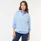 Sweater de punto en color celeste, con cuello en pico y mangas cortas. Presenta un diseño de tejido acanalado y corte holgado.