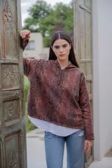 Buzo hoodie con estampado de piel de serpiente en tonos marrones y negros, con capucha forrada en color borgoña y cordón ajustable.