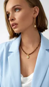 Collar de cuentas de piedra natural ojo de tigre con dije ovalado dorado y piedra engarzada al centro.
