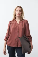 Camisa negra de corte clásico con escote en V, botones frontales y mangas largas con puños. Presenta detalles de recortes calados en la zona de los hombros.