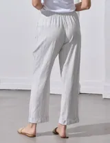 Pantalón de lino color beige con rayas verticales blancas, pretina elastizada con cordón ajustable, bolsillos laterales y ruedo con botamanga.