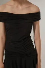 Vestido corto azul marino con escote strapless, diseño al cuerpo con frunces en el torso y falda con volados en el ruedo.