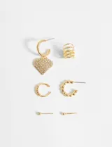 Set de aros y earcuff dorados con apliques de strass. Incluye aros tipo argolla con dije de corazón, aros tipo argolla con bolitas, aros tipo botón y earcuff de múltiples aros.