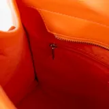 Cartera tipo shopper color naranja y beige, con detalles en símil cuero, acceso con cierre, correa regulable y asa fija. Cuenta con un bolsillo externo con cierre, un bolsillo interno con cierre y dos bolsillos internos abiertos.