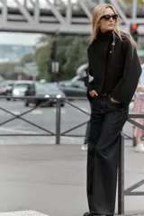 Chaqueta estilo bomber de punto color negro, con cuello subido, manga larga y cierre frontal cruzado con botones ocultos a presión. Presenta bolsillos delanteros de vivo.