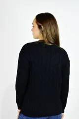 Sweater de punto color beige, con diseño de trenzas, cuello redondo y mangas largas.