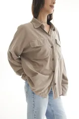 Camisa negra de pana, corte oversize, con cuello camisero, cierre frontal con botones, dos bolsillos con solapa en el pecho y mangas largas con puños abotonados.