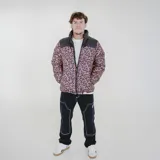 Campera puffer reversible de color negro con acabado brillante. Presenta cuello alto, cierre frontal y un diseño interior con estampado animal print. Incluye logo de la marca en la manga.
