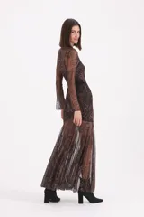 Vestido largo de tul transparente con estampado paisley en tonos chocolate y negro, de manga larga y cuello redondo. Incluye un forro interior tipo vestido corto y un cinturón fino negro con hebilla dorada.