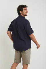 Camisa sport de manga corta, confeccionada en una mezcla de lino y algodón. Presenta cuello clásico, cierre frontal con botones de coco y un bolsillo aplicado en el pecho.