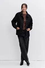 Campera de denim negro con cierre frontal y botones a presión, cuello clásico y bolsillos laterales.