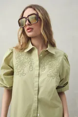 Camisa blanca de mangas 3/4 abullonadas con bordado floral en el frente.