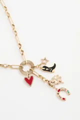 Collar de cadena dorada con dije circular y múltiples charms colgantes: corazón rojo, bota negra, trébol verde y bastón de caramelo con detalles de pedrería.