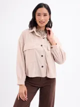 Campera de pana negra con cierre frontal de botones metálicos, cuello clásico y dos bolsillos frontales con solapa. Presenta mangas largas con puños abotonados y un diseño liviano sin forro.