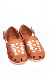 Sandalia tipo chatita color marrón, confeccionada en cuero con diseño de tejido trenzado en la puntera y el empeine. Presenta cierre de hebilla lateral y suela de goma con textura.