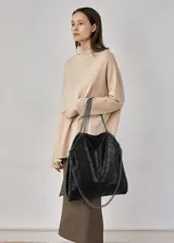 Bolso tote negro con textura arrugada y detalles de cadena plateada en las asas y los bordes.