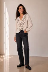 Blusa celeste de manga larga con escote en V y volados en cascada ribeteados en color oscuro. Cuenta con puños elásticos.