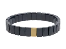 Pulsera elástica compuesta por eslabones rectangulares de cerámica negra con acabado facetado y una pieza central rectangular de acero con baño de oro.
