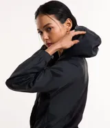 Campera rompevientos deportiva blanca, confeccionada en poliamida, con capucha, cierre delantero en cremallera, tirador gomoso y puños ajustados.