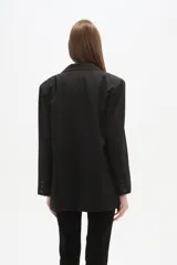 Blazer negro de poliéster, de corte holgado, con cuello solapa y cierre de un botón. Incluye dos bolsillos frontales con solapa y un bolsillo superior simulado.